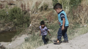 Migrant children wait for their father on the Mexican side of the Rio Bravo before crossing the US - Mexico border to surrender to the American authorities, between Ciudad Juarez and El Paso.