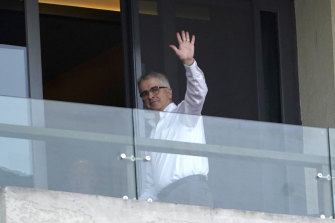 Professor Dwyer waves at journalists from a hotel room balcony in Wuhan on January 29. 