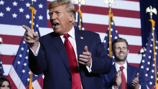 Republican presidential candidate former President Donald Trump points to the crowd with son Eric at a caucus night party in Des Moines, Iowa