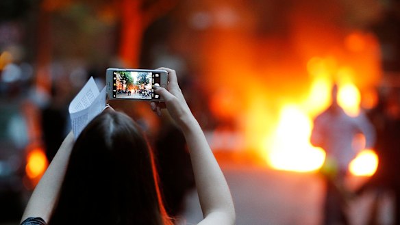 A young woman takes a picture of a burning barricade during a protest against the G20 in Hamburg,  Germany, in July.