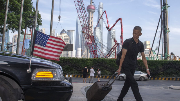 A traveller pulls a trolley past a US embassy car outside a hotel in Shanghai.