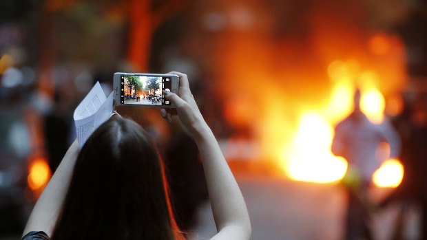 A young woman takes a picture of a burning barricade during a protest against the G20 in Hamburg,  Germany, in July.