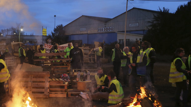 Demonstrators stand in front of a makeshift barricade set up by the so-called yellow jackets to block the entrance of a fuel depot in Le Mans, France.