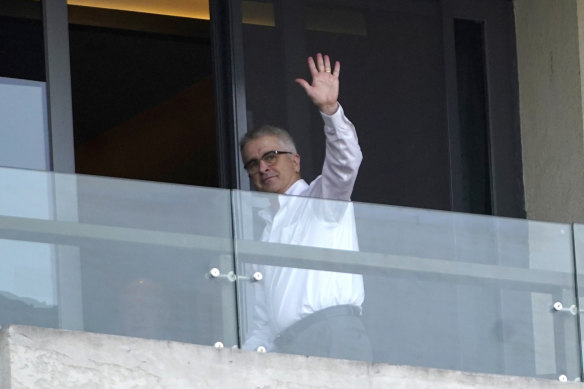 Professor Dwyer waves at journalists from a hotel room balcony in Wuhan on January 29. 