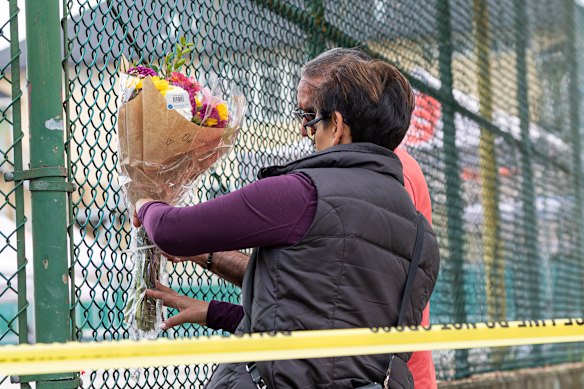 Members of the public attach flowers to a fence, near the scene where a vehicle drove into crowd at a street festival the night before.