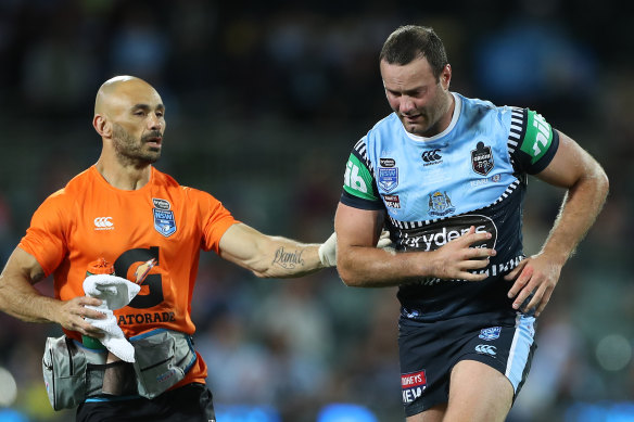 Boyd Cordner is assisted off Adelaide Oval for a head injury assessment by Roosters and Blues trainer Travis Touma.