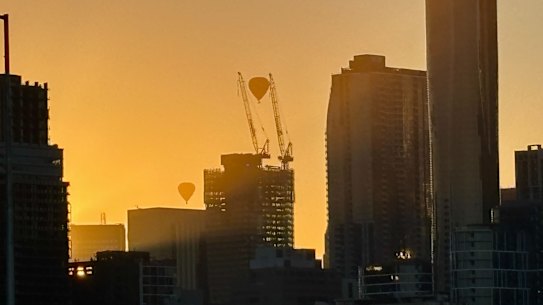 Dois balões de ar quente viajam através da névoa esfumaçada que cobre o horizonte da cidade antes de uma temperatura prevista de 45 graus em Melbourne hoje. 