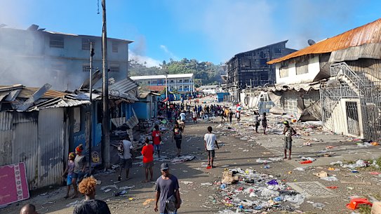 People walk through the looted streets of Chinatown in Honiara on November 26.