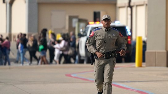 A law enforcement officer runs as people are evacuated from a shopping center where a shooting occurred Saturday, May 6, 2023, in Allen, Texas. 