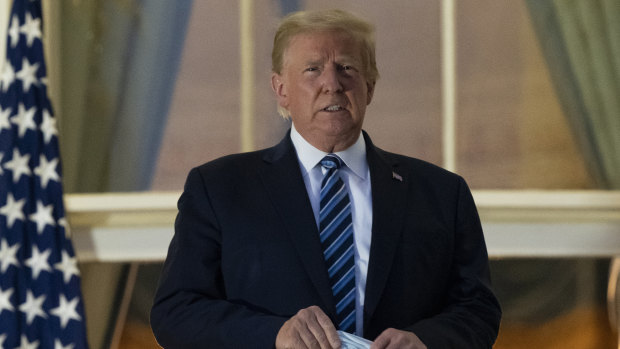 US President Donald Trump holds his mask after removing it from his face  upon returning to the White House in Washington from the Walter Reed National Military Medical Centre in Bethesda, Maryland.