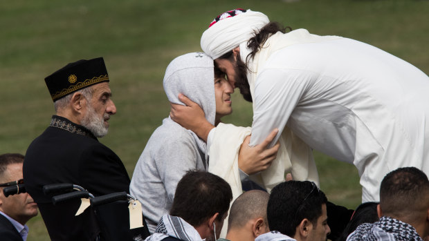 Zaid Mustafa, left, son and brother of victims from last week's mosque shootings, is greeted at Friday prayers.