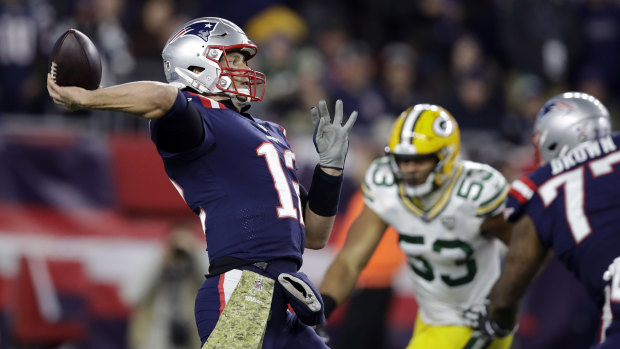 Cool under pressure: Tom Brady throws as the Green Bay defence closes in.