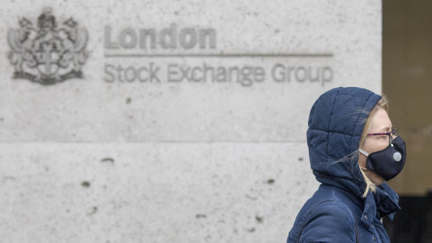 A pedestrian wears a protective face mask as she walks past the London Stock Exchange.