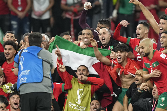 Morocco’s players hold the Palestinian flag after winning their last-16 match against Spain.