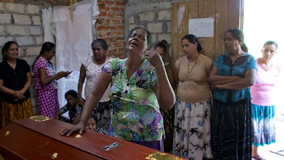 A woman weeps standing beside the coffin with the remains of her 12-year old niece, Sneha Savindi.