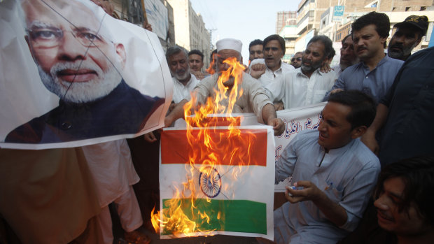 Pakistanis burn a representation of an Indian flag and a poster of Indian Prime Minster Narendra Modi in protest over the Kashmir decree.