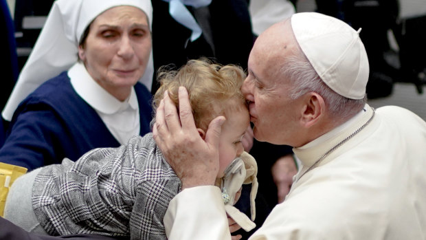 Pope Francis kisses a baby at the Vatican on Saturday.