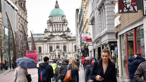 Pedestrians walk along with Belfast City Hall in the background last week.