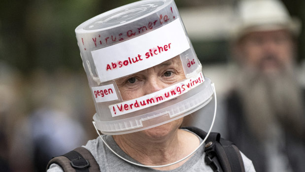 Demonstrator walks through Berlin-Charlottenburg with a plastic bucket placed on his head reading ‘Absolutely safe against the stupidity virus’, in Berlin. 