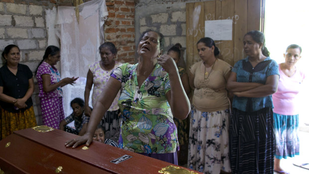 A woman weeps standing beside the coffin with the remains of her 12-year old niece, Sneha Savindi.