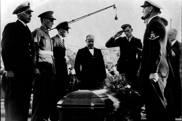 Sergeant John Curtin, only son of the late Prime Minister, salutes as the casket containing the body of his father is lowered into the grave at Karrakatta Cemetery, Perth.