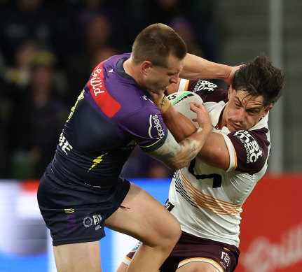 Kotoni Staggs of the Broncos is tackled by Cameron Munster of the Storm.