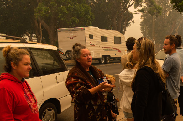 Displaced residents line up to use a payphone in Narooma.