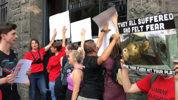 Protesters hold up graphic posters with slogans against the window of the King Street restaurant.