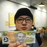 Philip Leong, from TWS Gai Wong chicken restaurant, holds a counterfeit $100 note at his restaurant in North Melbourne.