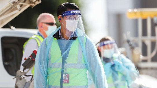 Biosecurity and airport staff in PPE and masks are seen around the chartered flight QR7176 after it arrived in Melbourne carrying Australian Open players.