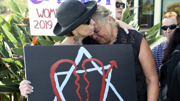 Leslie Gollub and Gretchen Gordon hug at a vigil held to support the victims.