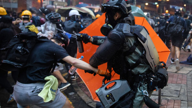 Riot police use pepper spray against protesters.