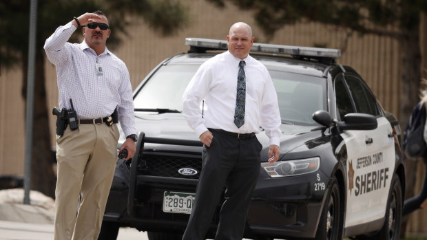 Columbine High School principal Scott Christy, right, watches as students leave the school on Tuesday.