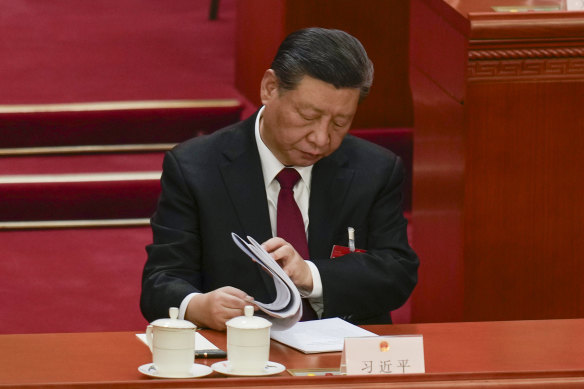 Chinese President Xi Jinping looks through documents during the opening session of the National People’s Congress.