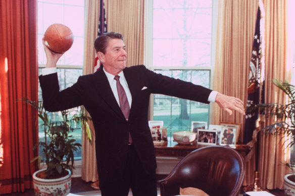 President Ronald Reagan throwing a football from his desk in the Oval Office.