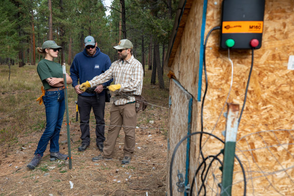 Russell Talmo, right, a specialist in conflict prevention, demonstrates how to build a bear-deterrent electric fence.