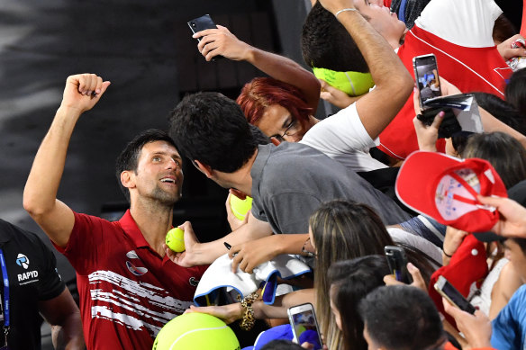 Novak Djokovic (left) celebrates with fans after winning the doubles match with partner Viktor Troicki.