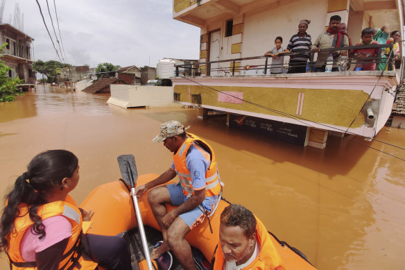 People stranded on a balcony in flood waters watch as others are rescued at Kolhapur in western Maharashtra state.