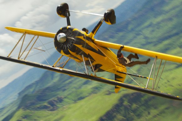 Tom Cruise clings to the wing of a plane in flight.