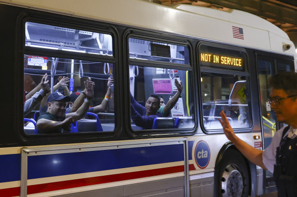 Migrants wave as a bus leaves to take them from Union Station in Chicago to a refugee centre.