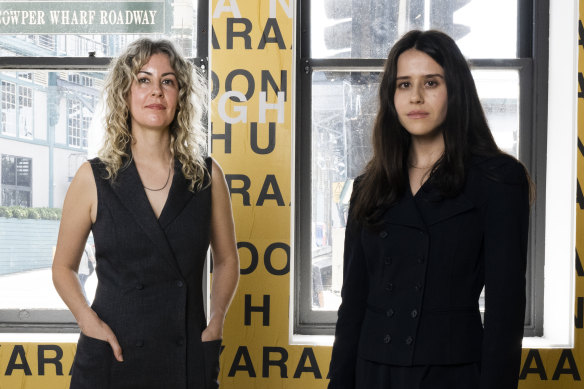 Co-authors of the Countess Report, Miranda Samuels and Shevaun Wright in front of Gamilaraay/Wailwan/Biripi artist r e a’s GARI (language), 2024, for the 24th Biennale of Sydney, Ten Thousand Suns, 2024, Artspace. GARI (language) was commissioned by Biennale of Sydney and Artspace. Courtesy of the artist. © r e a. 



