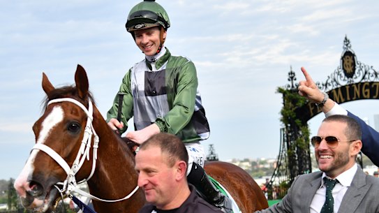 Jockey Jye McNeil returns to scale after riding Kings Will Dream to victory in the Turnbull Stakes at Flemington with part-owner Brae Sokolski in grey suit.