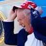 Brace yourself for the tariff storm: President Donald Trump holds his MAGA hat in the wind while disembarking Air Force One last month.