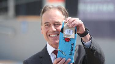 Minister for Health and Aged Care Greg Hunt holds up a pair of COVID-19 vaccination-themed socks.