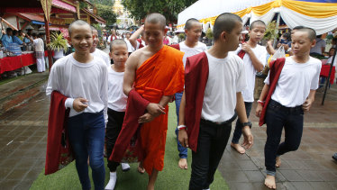 Members of Wild Boars soccer team walk with Buddhist monk, former soccer coach Ekkapol Chanthawong, in red, after the completion of their serving as novice Buddhist monks.