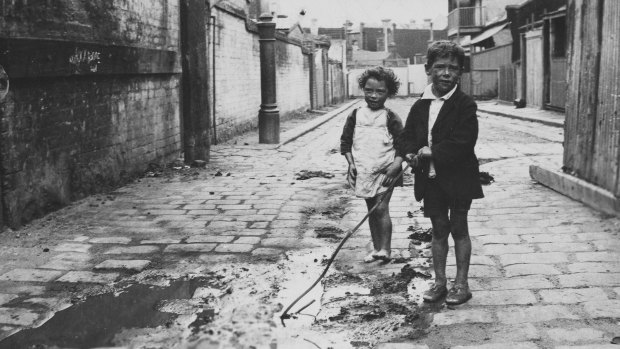 Entrance to a slum pocket known as Carlow Place, Carlton. The children are playing in runoff from a stable. 