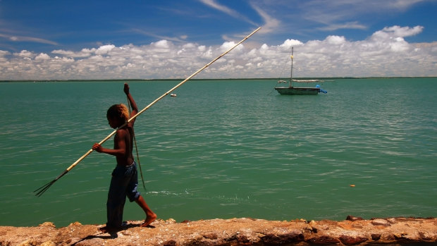 A boy with a fish spear walks along a sea wall at Saibai Island in the Torres Strait. 