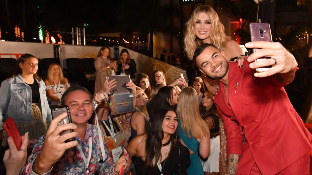 Guy Sebastian and Delta Goodrem pose for selfies with fans on the red carpet. 