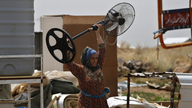 A Syrian woman carries a fan as she removes her belongings amid the evacuation of an informal refugee camp in Deir Al-Ahmar, Lebanon on Sunday.