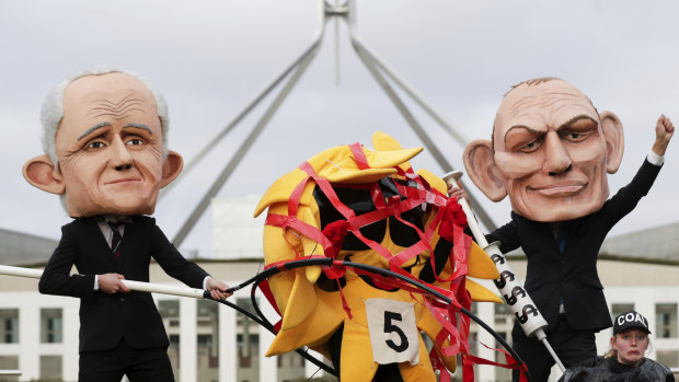 Puppets of Malcolm Turnbull and Tony Abbott rig the sun versus coal race in a protest outside Parliament 